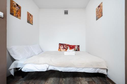 a white bed in a room with a wooden floor at Obywatelska Comfort Apartment by BookingHost in Łódź