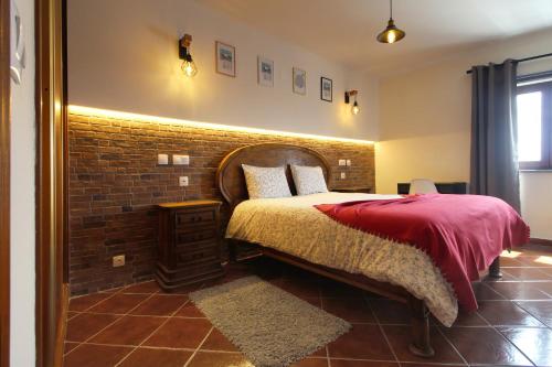 a bedroom with a bed with a brick wall at Apartamento Magnólia 80186 AL in Vila Nova de Milfontes
