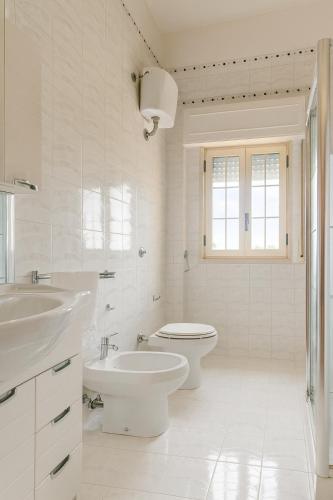a white bathroom with a toilet and a sink at A un passo dal cuore in Mesagne