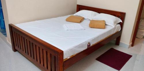 a wooden bed with two pillows on top of it at Guru Rooms in Tiruvannāmalai