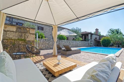 patio con ombrellone e piscina di Villa Kluni by Rent Istria a Momjan