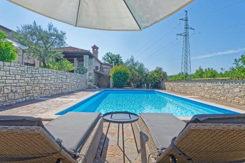 una piscina con sedie e un tavolo di fronte a una casa di Villa Kluni by Rent Istria a Momjan