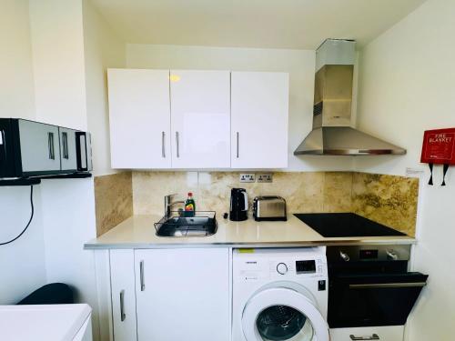 a kitchen with a sink and a washing machine at Osborne Aparthotel in Eastbourne