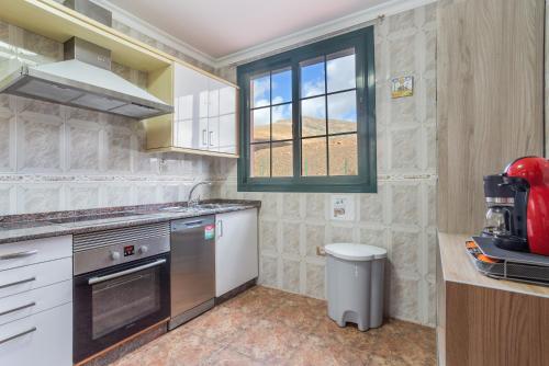 eine Küche mit weißen Geräten und einem Fenster in der Unterkunft Vivienda Vacacional Sara in Tetir