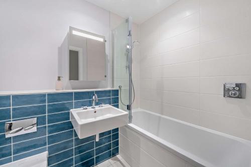 a white bathroom with a sink and a mirror at 12 Middlecombe - Luxury Apartment at Byron Woolacombe, only 4 minute walk to Woolacombe Beach! in Woolacombe