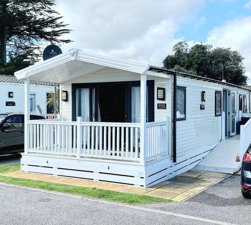 a white mobile home with a porch on a street at H05 Par Sands in Tywardreath
