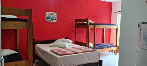 a room with two bunk beds and a red wall at Residencial Jmulguero in Guaratuba