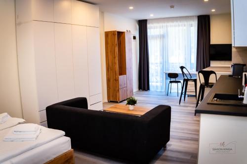 ein Wohnzimmer mit einer schwarzen Couch und einer Küche in der Unterkunft Urban76 Apartments in Târgu Mureș