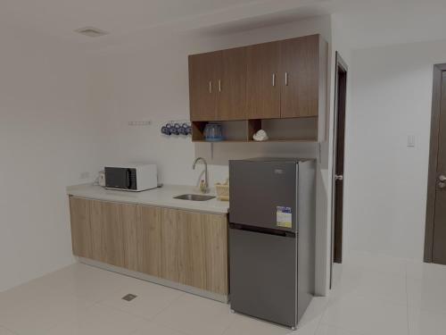 a small kitchen with a refrigerator and a sink at Sitari Condo Bacolod in Bacolod