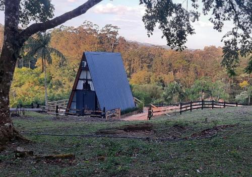 a small black barn with a fence and a tree at Chalé Amorata in Ibirama