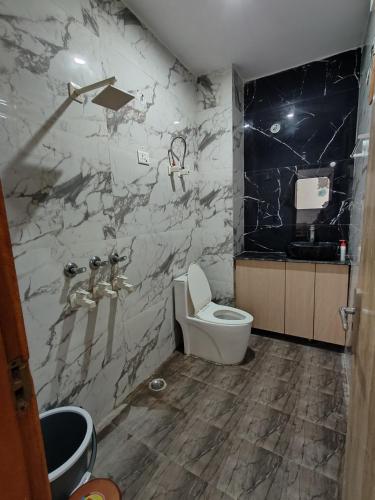ein Badezimmer mit einem weißen WC und einer Marmorwand in der Unterkunft Srivastav Homestay in Noida