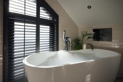 a large white tub in a bathroom with a window at Landal Dylan Coastal Resort in Laugharne