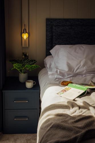 a bedroom with a bed with a night stand and a plant at Landal Dylan Coastal Resort in Laugharne
