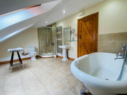 伊姆Hollow Brook Cottage Heart of the Peak District的带浴缸、两个卫生间和水槽的浴室