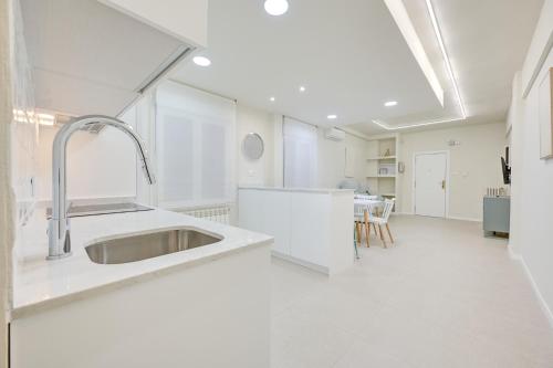 a white kitchen with a sink and a table at Oasis by Clabao in Logroño
