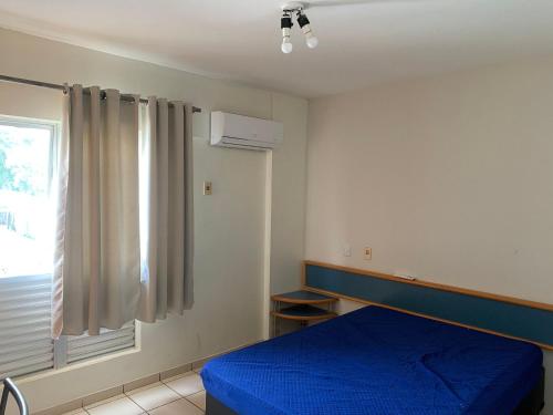 a bedroom with a blue bed and a window at Eldorado Thermas Park Localização Top área de Lazer Completa in Caldas Novas