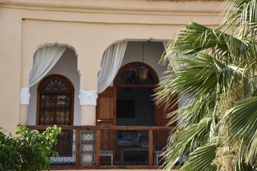 a house with a wooden door and a palm tree at Chambres Émeraude et Rubis - Riad Lotus Bleu in Fès