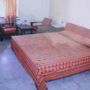 un letto di legno in una stanza con un divano e delle sedie di hotel royal a Jāmb