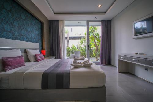 a bedroom with a large bed and a large window at Kamini Legian Hotel in Legian