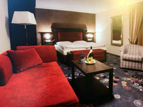 ein Hotelzimmer mit einem roten Sofa und einem Bett in der Unterkunft Landhaus Auhirsch in Böbrach