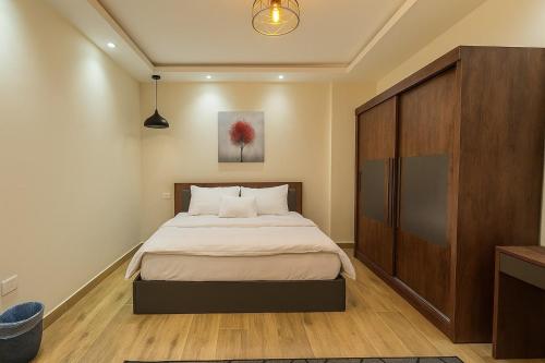 a bedroom with a bed and a large wooden cabinet at 903 . Spacious 3BR Apt. 2 Baths Gated Community in Sheikh Zayed