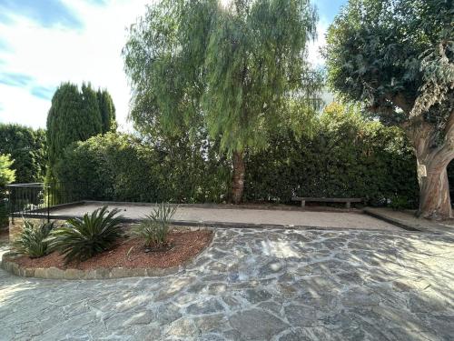 een park met een bank en een boom en bomen bij Villa Terra Alba in Le Lavandou