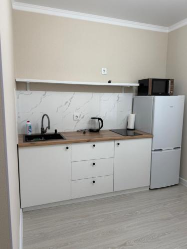 PrigorodnyyKvartira Astana的厨房配有白色橱柜和白色冰箱