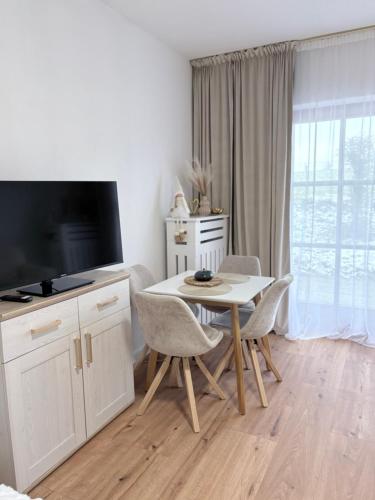 ein Wohnzimmer mit Tisch und Stühlen und einem Fernseher in der Unterkunft Chiemsee-Perle, stylisches Luxus-Appartement in Rimsting