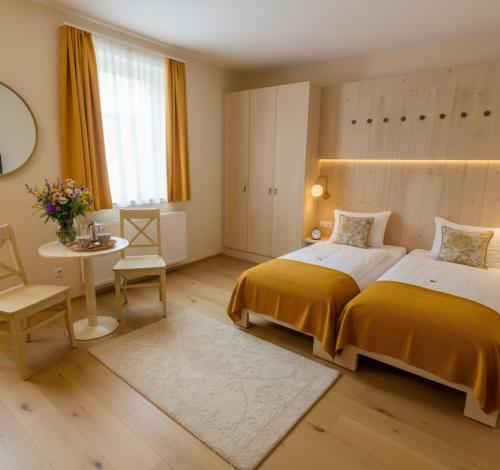 a bedroom with two beds and a table and a window at Landhotel Schustermühle in Seefeld-Kadolz