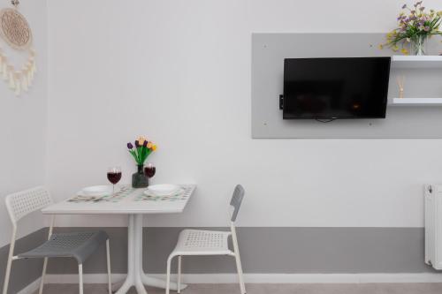 Una mesa blanca con dos sillas y un televisor en la pared. en Unique Studio with Balcony in Jastrzębia Góra by Noclegi Renters, en Tupadły