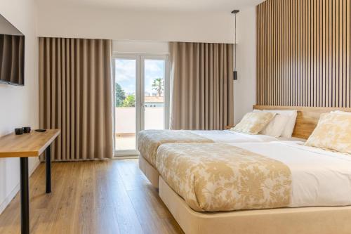 a bedroom with a large bed and a window at Hotel Caldas Internacional in Caldas da Rainha