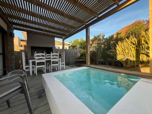 a patio with a swimming pool with chairs and a pergola at Los Bungalows in José Ignacio