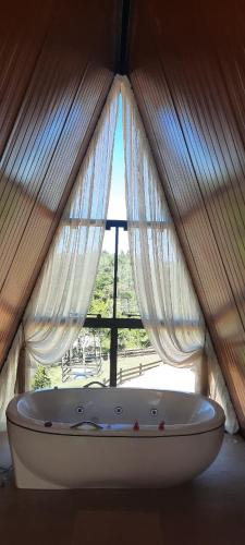 a white bath tub in front of a window at Chalé Amorata in Ibirama