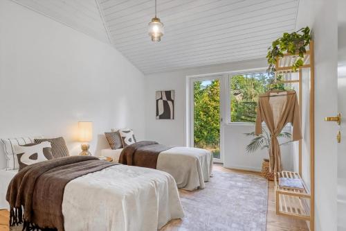 a bedroom with two beds and a window at Arkitekttegnet Sommerhus Tæt På Vandet in Marielyst