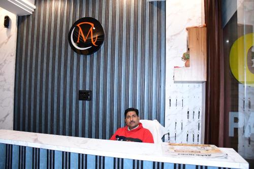 un uomo seduto su una sedia al bancone di Hotel CM Palace Khatu Shyam a Khātu