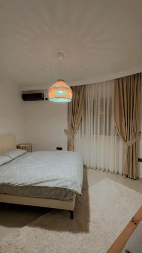 a bedroom with a bed and a chandelier at Kıbrıs Girnede 1 yatak odalı Süper lüks havuzlu daire in Vuda