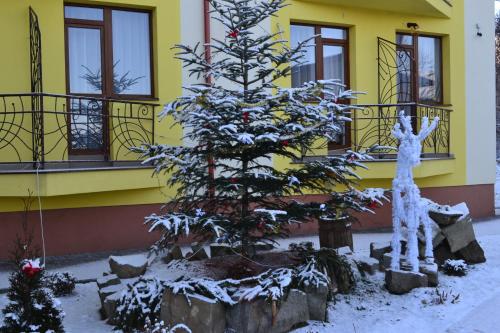 a christmas tree in front of a yellow building at Hotel Restaurant Vizit in Truskavets