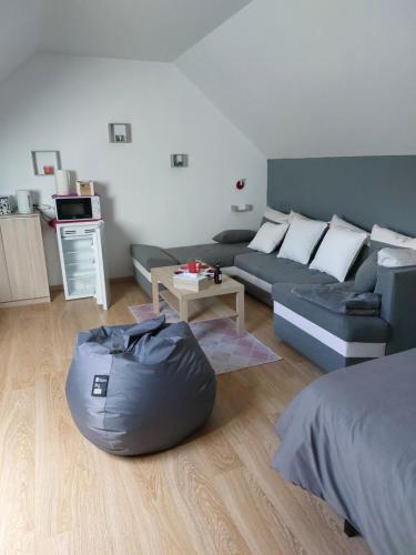 a living room with a couch and a table at Chambre Magnolias in Saint-Sauveur-dʼÉmalleville