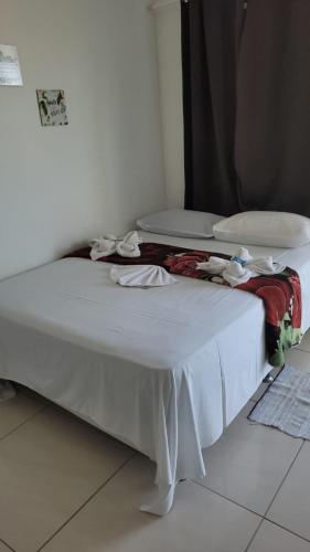 a white bed in a room with clothes on it at Pousada Portico de Buzios in Armacao dos Buzios