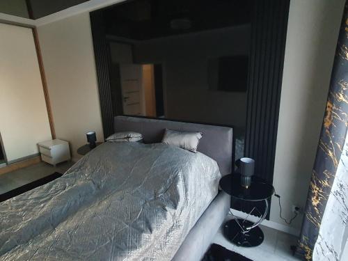 ein Schlafzimmer mit einem großen Bett und zwei Tischen in der Unterkunft Elegant Apartments FREE PARKING in Leszno
