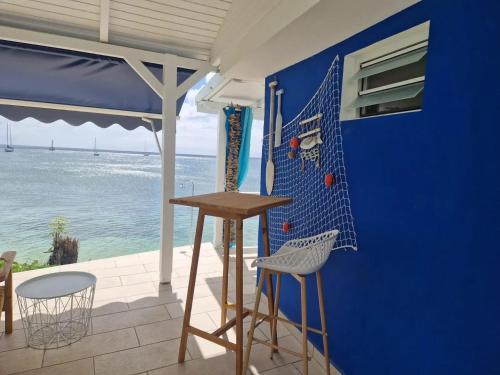a blue wall with a table and chairs and the ocean at Maison confortable à Saint Louis, 120 m², vue mer in Îlet à Christophe