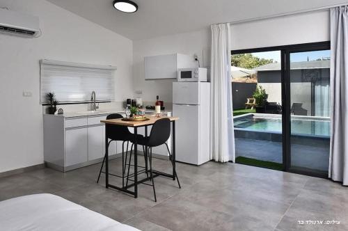 - une cuisine avec une table et deux chaises dans une pièce dans l'établissement r בוטיק, à Manot