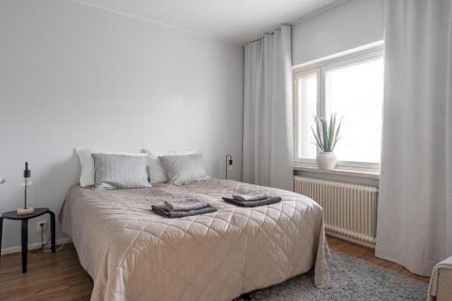 Un dormitorio blanco con una cama con dos toallas encima. en Bright & Cozy 1BR Home in Central Lahti, en Lahti