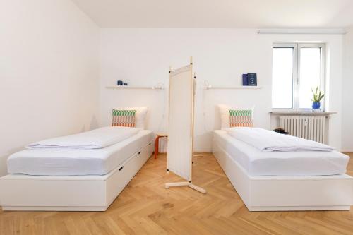 2 camas en una habitación blanca con espejo en MOWO Marshall 8 - Apartmenthaus Kitzingen - großzügige Wohnungen für je 6 Personen mit Balkon, en Kitzingen