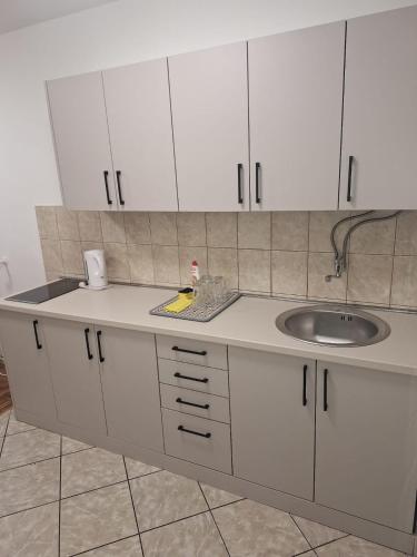 a kitchen with white cabinets and a sink at San centar apartment in Banja Luka