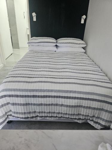 a bed with a black and white striped comforter at HomeAway Vredenburg in Vredenburg