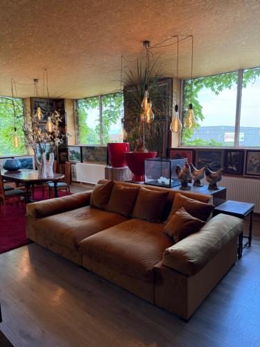 a living room with a brown couch and a table at kunstig appartement in Poelkapelle