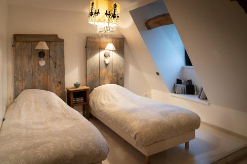 een slaapkamer met 2 bedden en een kroonluchter bij Maison 3 in Souvigny