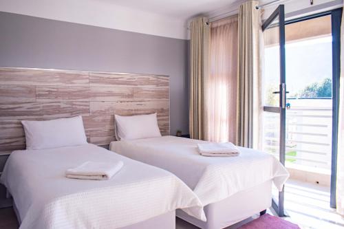 Dos camas en una habitación con ventana. en @Home BnB, en Maseru