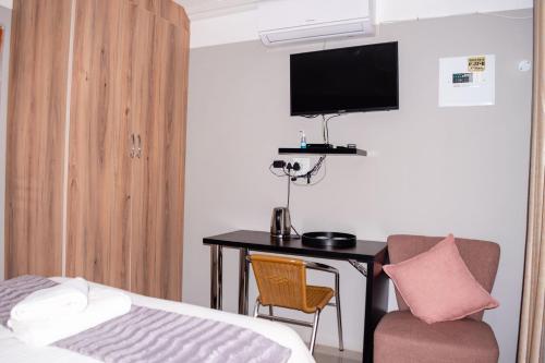 Una habitación de hotel con un escritorio, una cama y un televisor. en @Home BnB, en Maseru